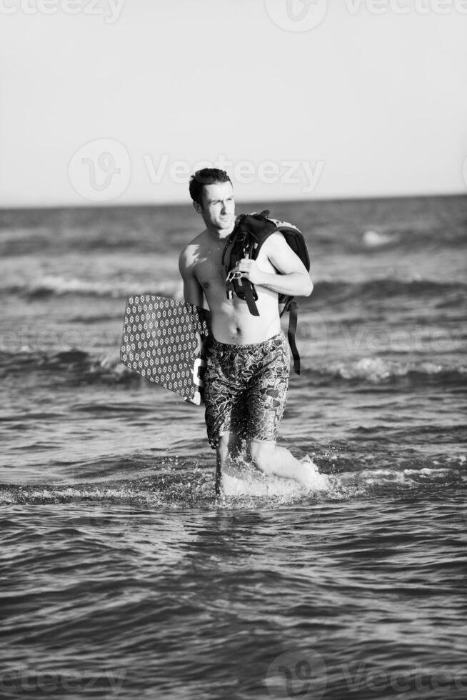 retrato de um jovem kitsurf na praia ao pôr do sol foto