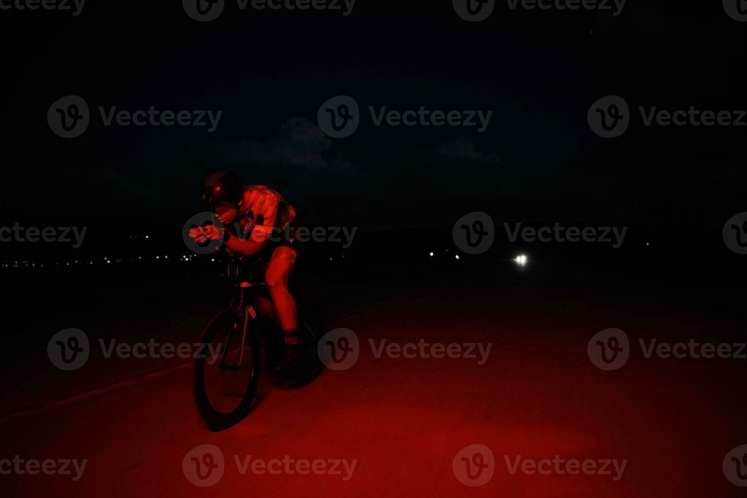 atleta de triatlo andando de bicicleta rápido à noite foto