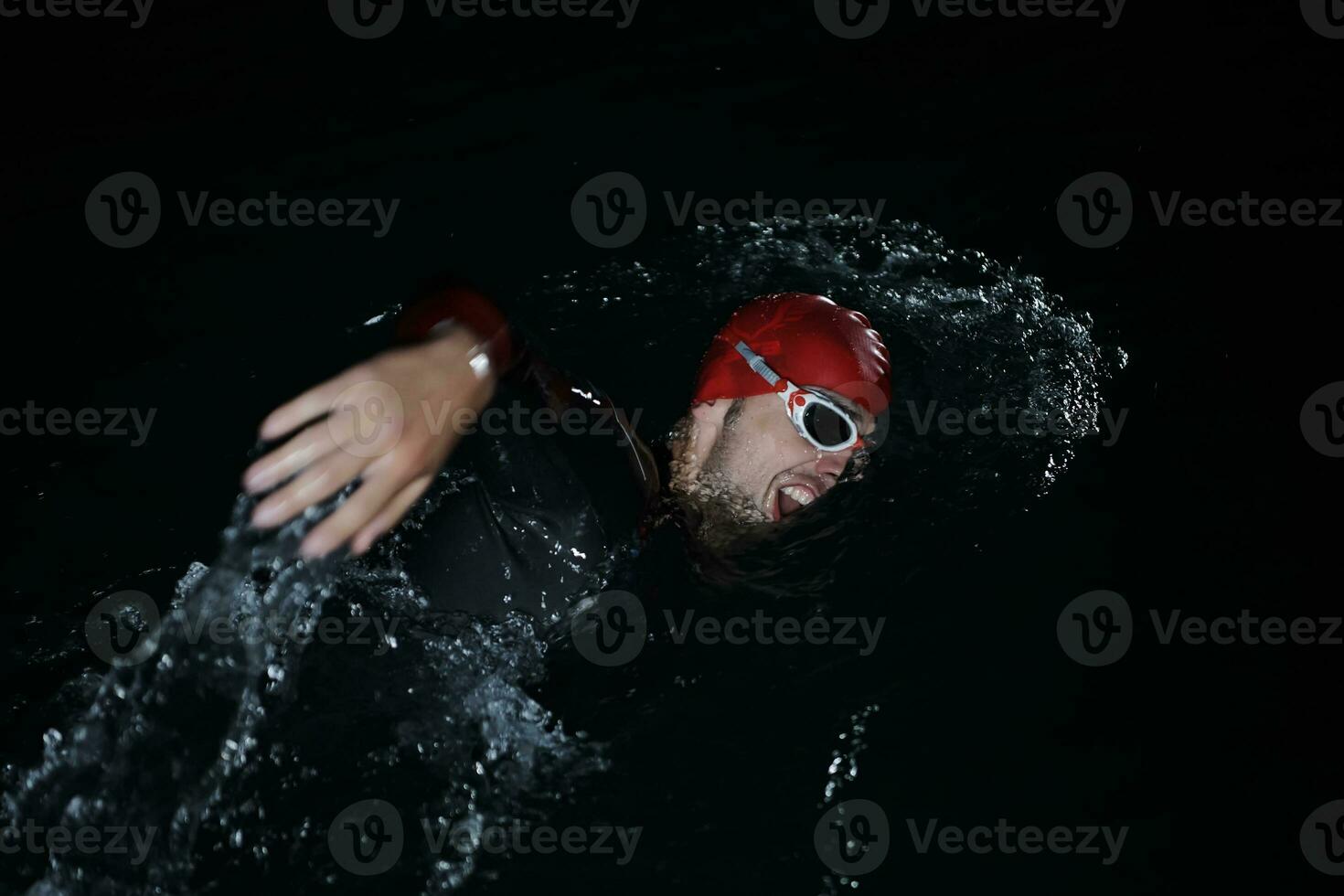 atleta de triatlo nadando na noite escura vestindo roupa de mergulho foto