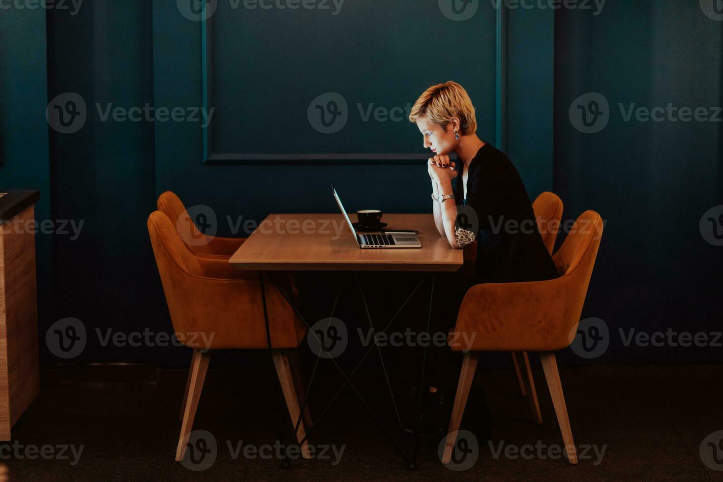 empresária sentado dentro uma cafeteria enquanto focado em trabalhando em uma computador portátil e participando dentro a conectados Encontros. seletivo foco. Alto qualidade foto