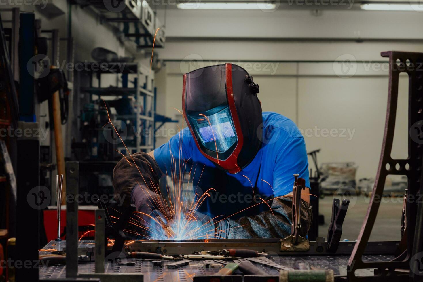 soldador profissional da indústria pesada trabalhando dentro da fábrica, usa capacete e começa a soldar. foco seletivo foto