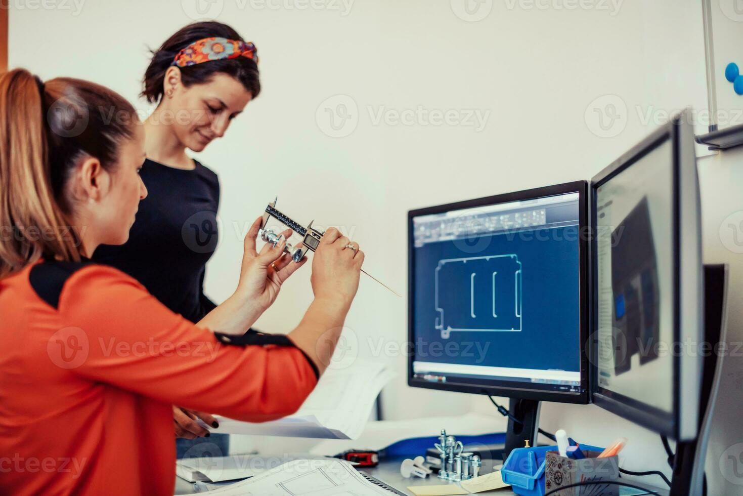 dentro da indústria pesada, um engenheiro industrial de fábrica mede com um paquímetro e em um computador pessoal projeta um modelo 3d foto