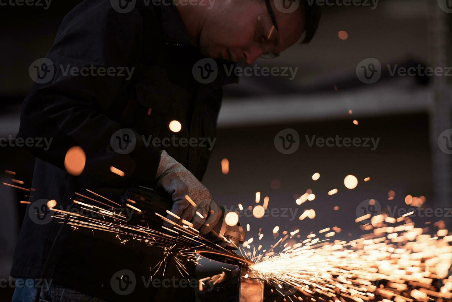 interior da fábrica de engenharia da indústria pesada com trabalhador industrial usando rebarbadora e cortando um tubo de metal. empreiteiro em uniformes de segurança e fabricação de capacetes de estruturas metálicas. foto