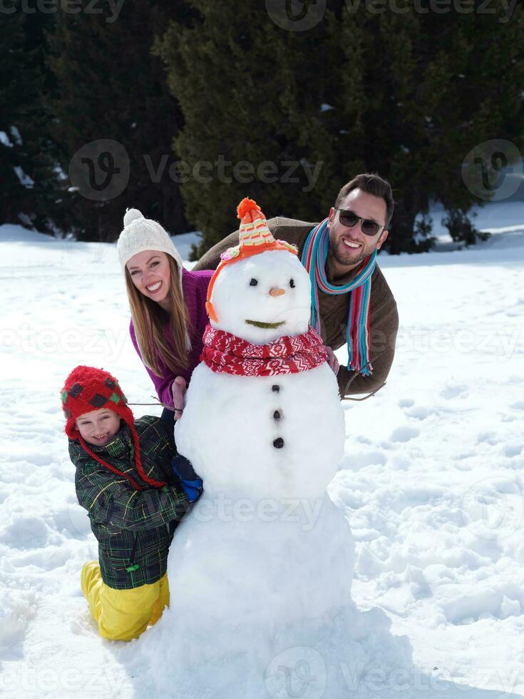 família feliz fazendo boneco de neve foto