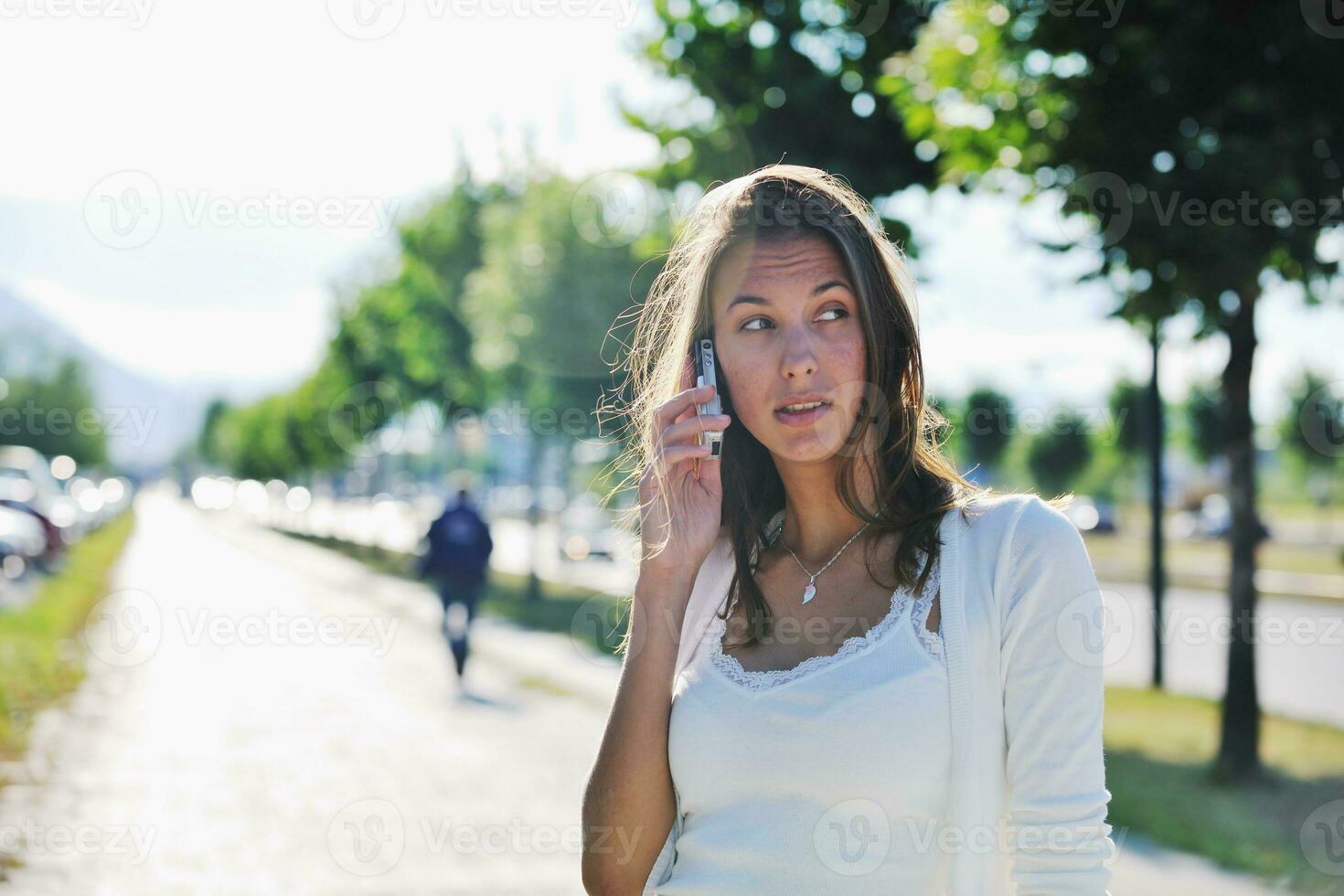 jovem fala pelo celular na rua foto