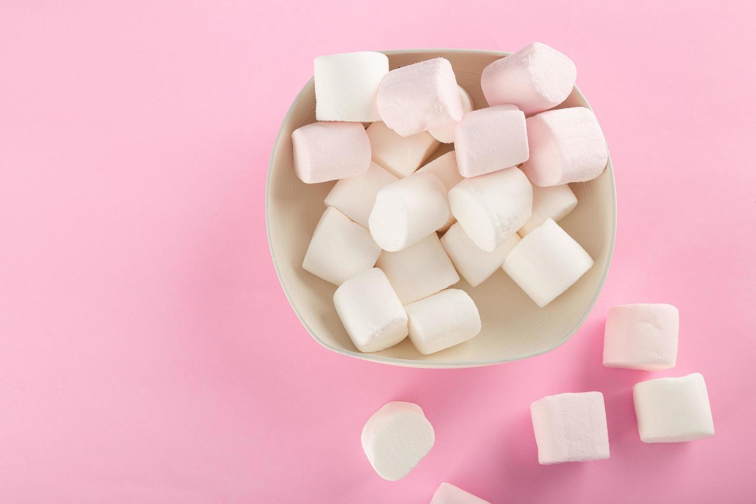 marshmallow em uma tigela em fundo rosa pastel foto