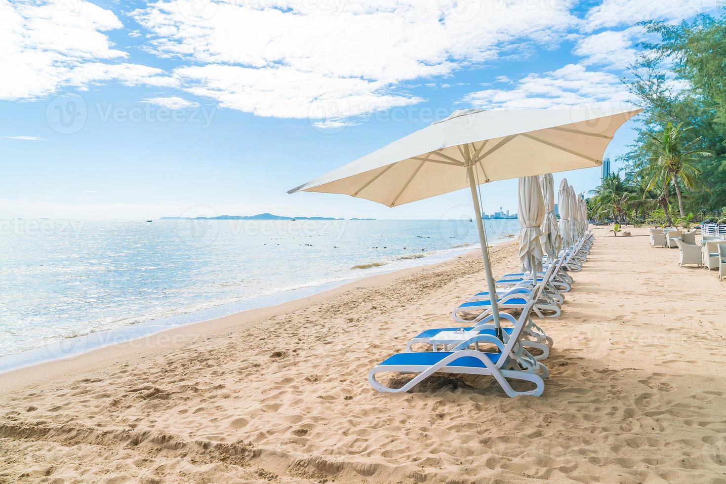 ao ar livre com guarda-sol e cadeira na bela praia tropical e mar foto