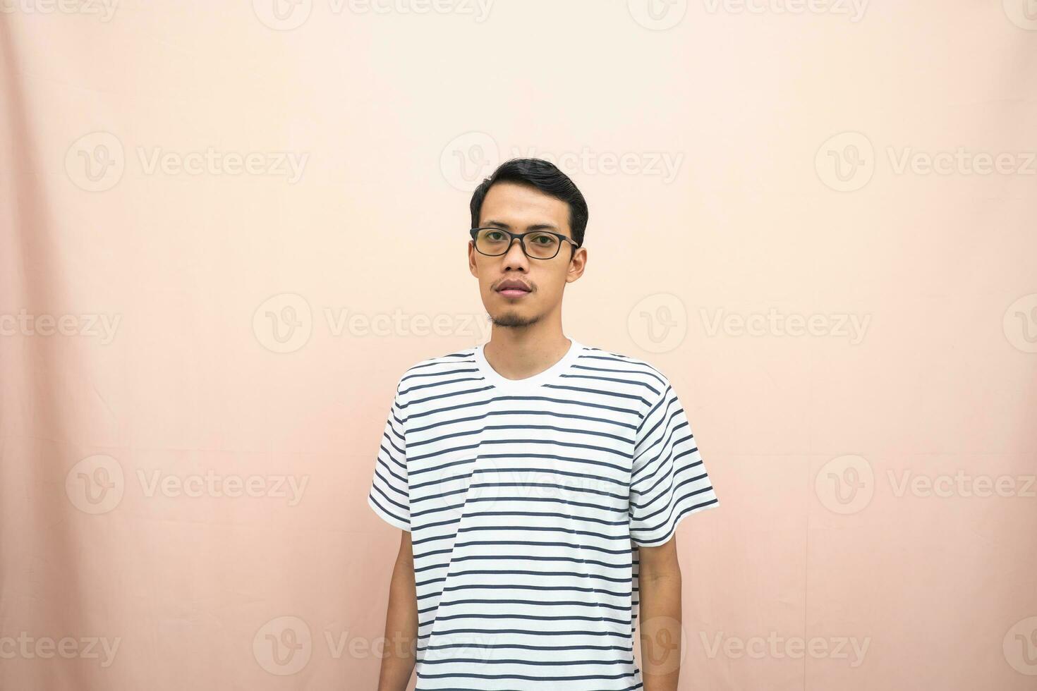 ásia homem dentro óculos vestindo casual listrado camiseta, em pé pose, sorridente e sério. foto