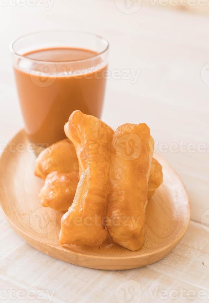 Palito de massa frita com chá de leite na madeira foto