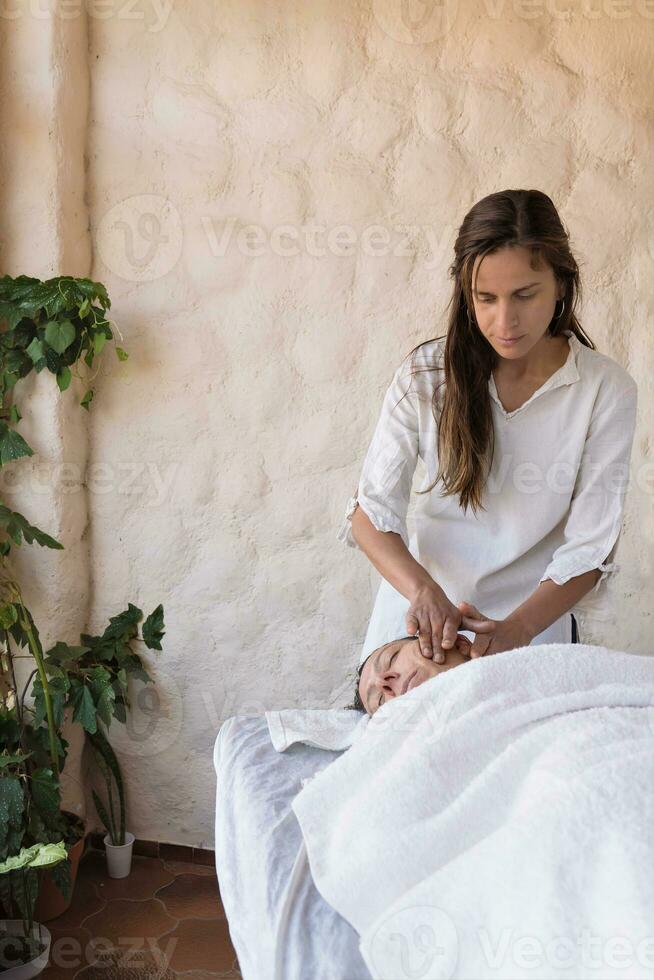 mulher recebendo facial massagem dentro spa de jovem terapeuta. foto