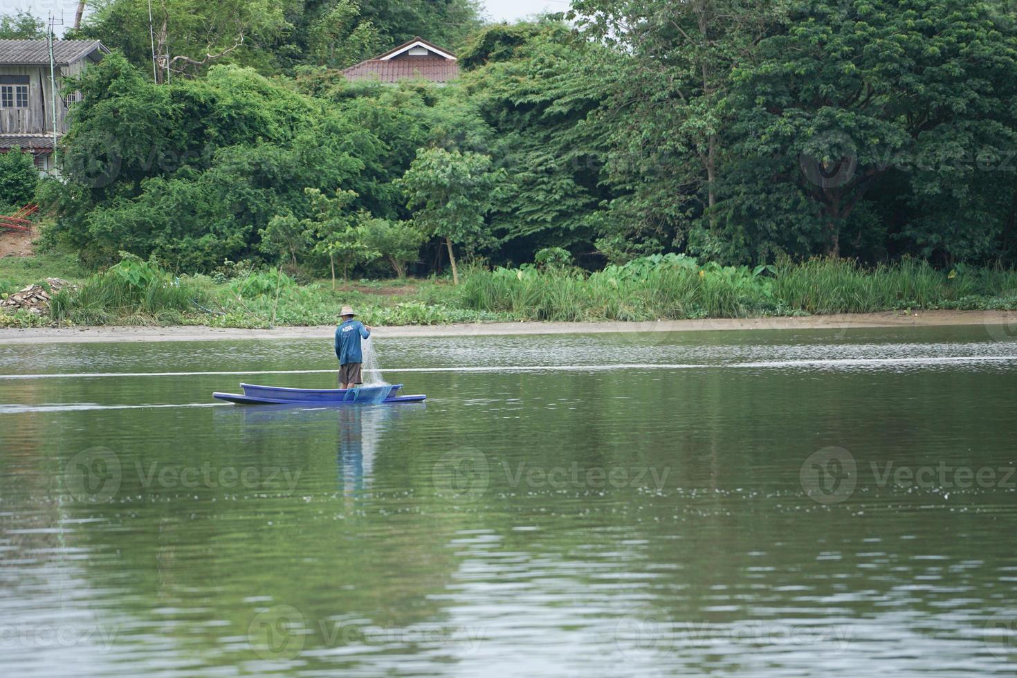 homem solitário fica no barco e coleta os peixes da rede foto