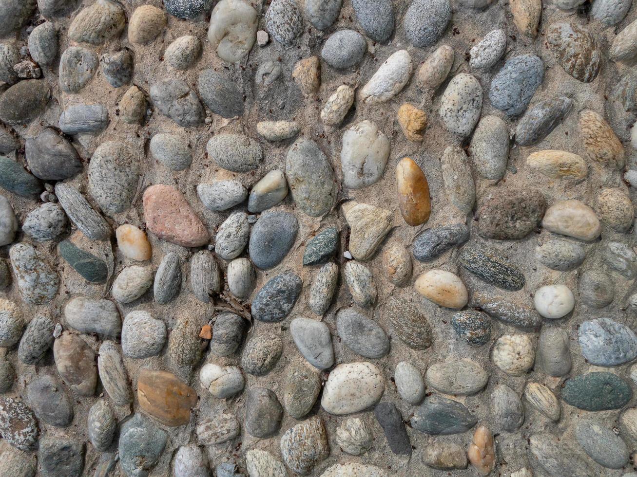 uma parede construída com uma mistura de pedras redondas e cimento foto