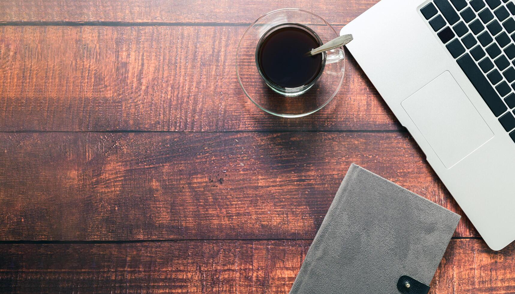 caneca de café, notebook, livro na mesa. foto