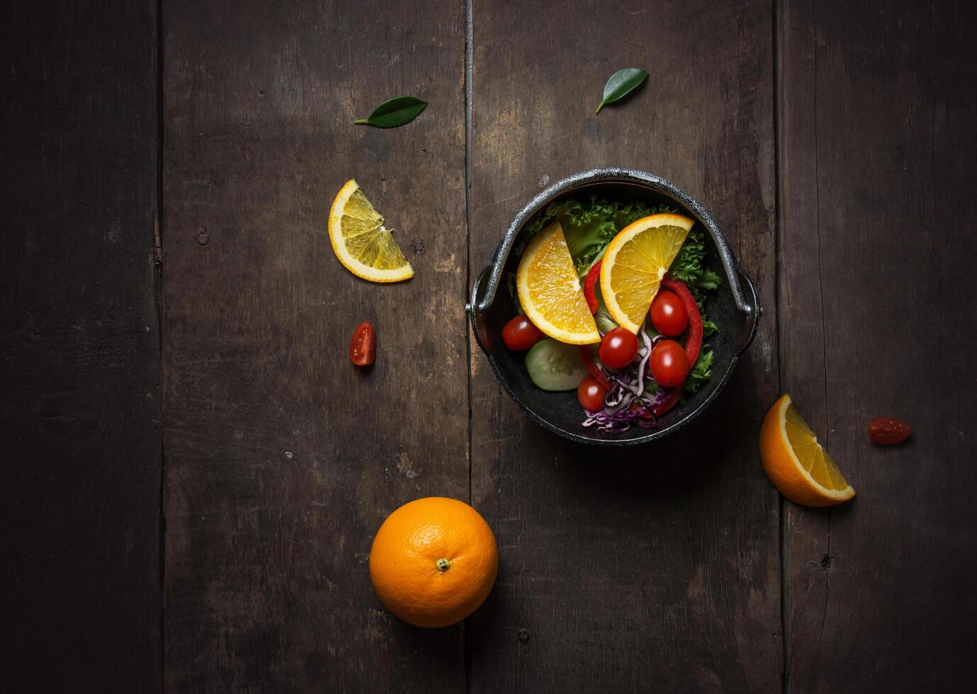 Salada fresca com fatia de laranja em um fundo de madeira foto