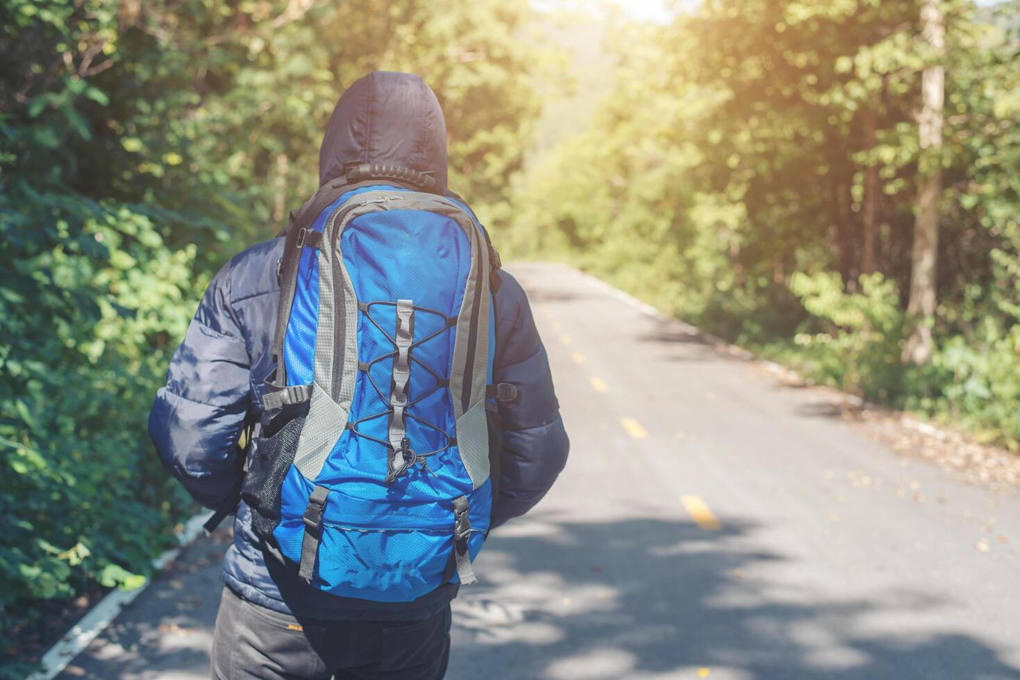 parte traseira do homem alpinista caminhando na estrada rural. conceito de turismo de férias. foto