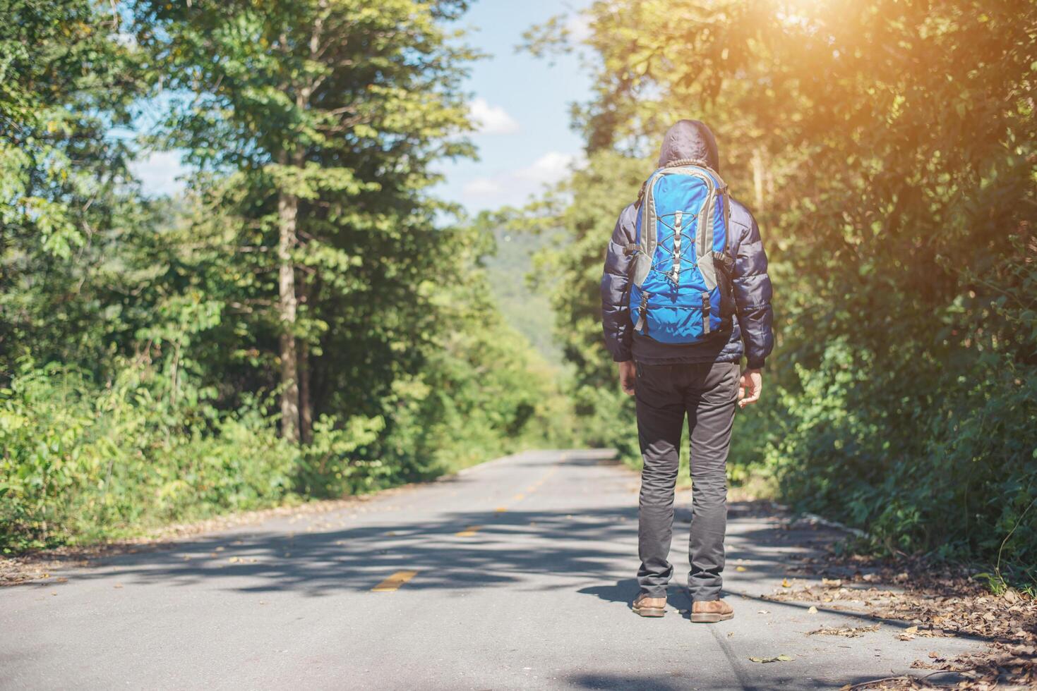 parte traseira do homem alpinista caminhando na estrada rural. conceito de turismo de férias. foto