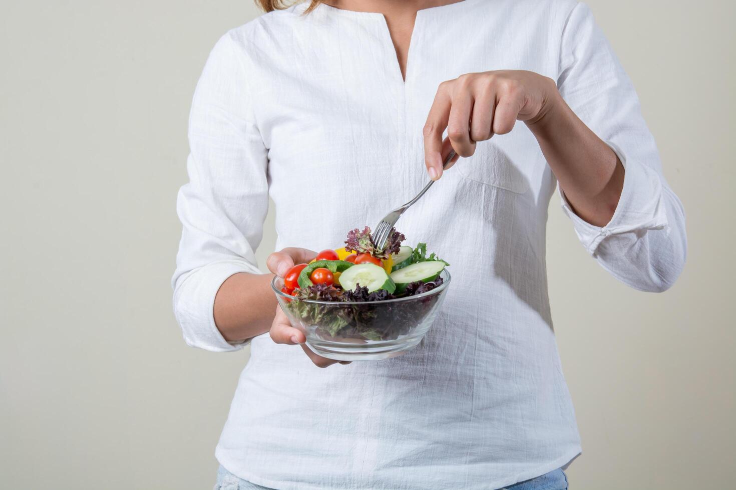 close-up de uma mulher com as mãos segurando, comendo salada de legumes fresca foto