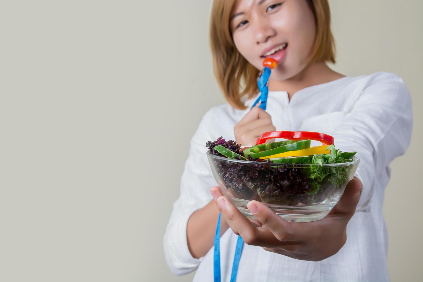 linda mulher comendo salada com fita métrica do garfo embrulhada. foto