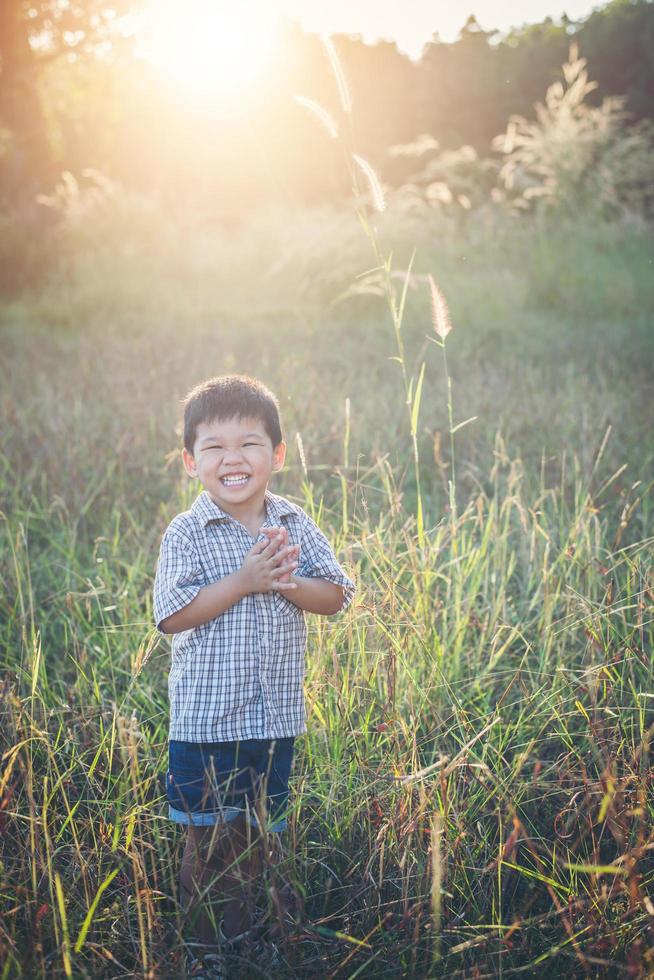 menino asiático feliz brincando ao ar livre. bonito asiático. menino em campo. foto