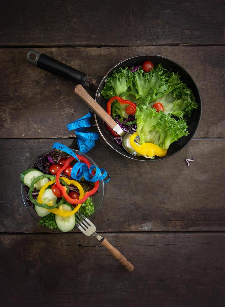 salada de legumes frescos na tigela com medição de fundo de madeira. foto