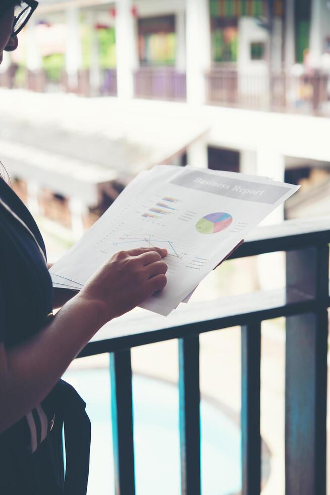 mãos da mulher financeira apontando nas notas do gráfico financeiro enquanto trabalhava foto