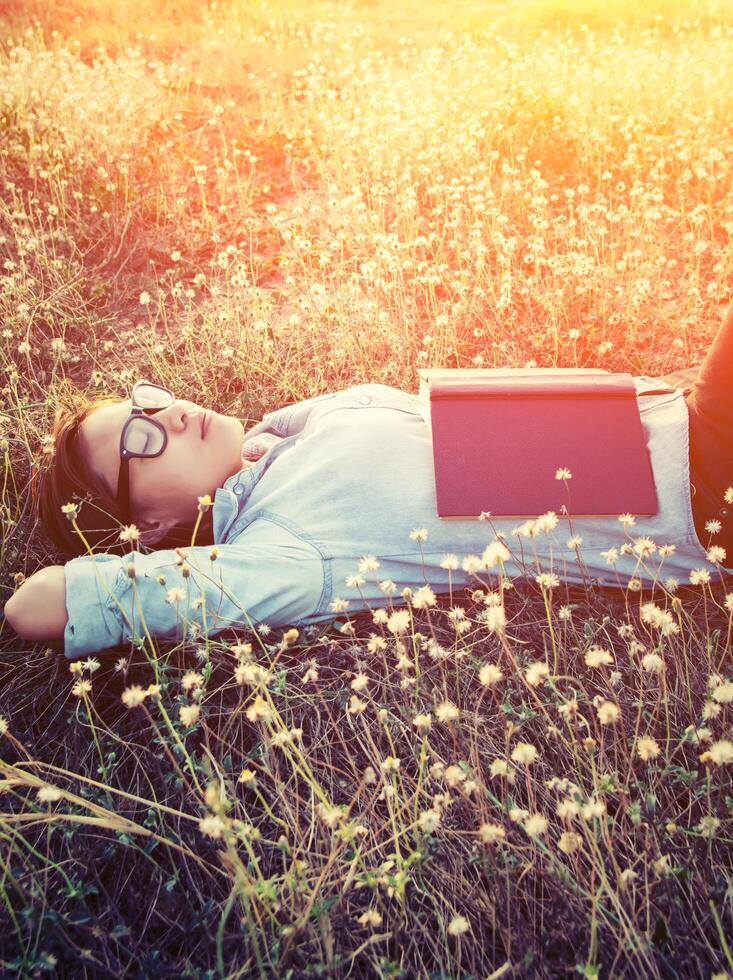 mulher jovem hippie deitada em um campo de flores depois de se cansar de ler foto