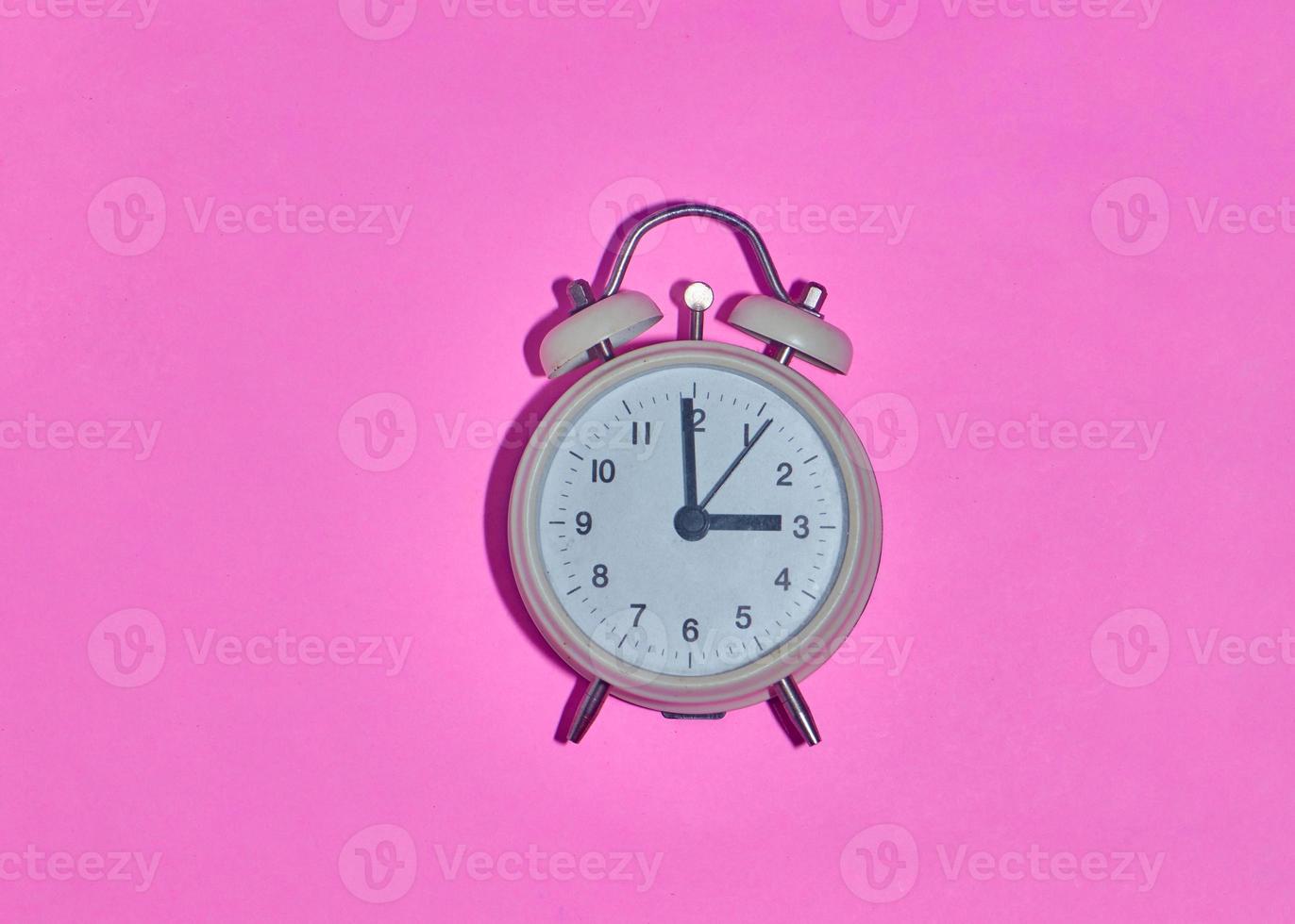 despertador vintage em fundo rosa claro foto