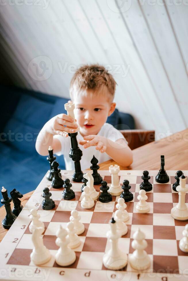 criança jogando xadrez às casa às a mesa foto