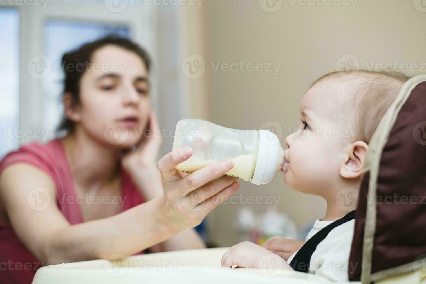 mãe feeds bebê a partir de uma garrafa do leite foto