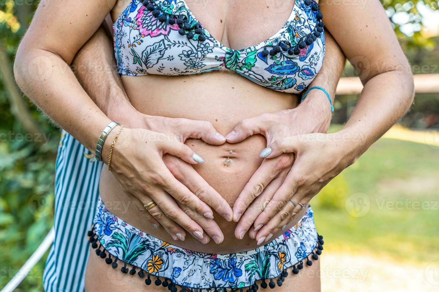 fechar acima do pais mãos formando coração placa em grávida mãe barriga foto