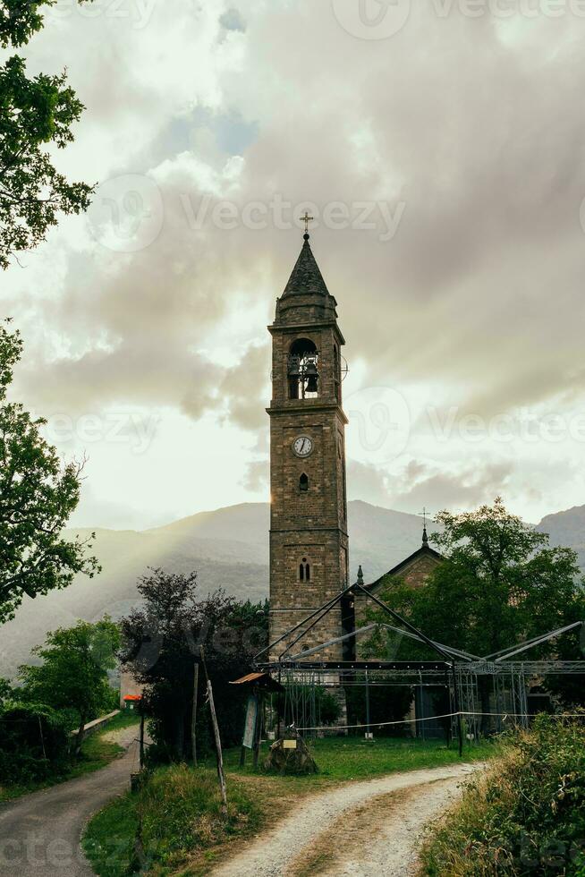 antigo Sino torre dentro uma medieval Vila cercado de colinas às pôr do sol foto