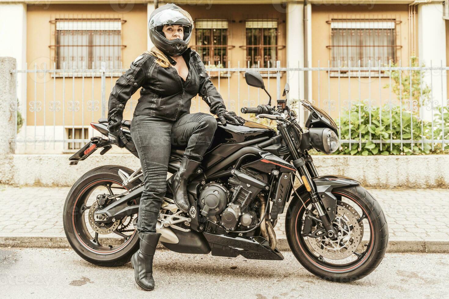 meio envelhecido mulher dentro motociclista roupas equitação uma moderno motocicleta ao ar livre foto