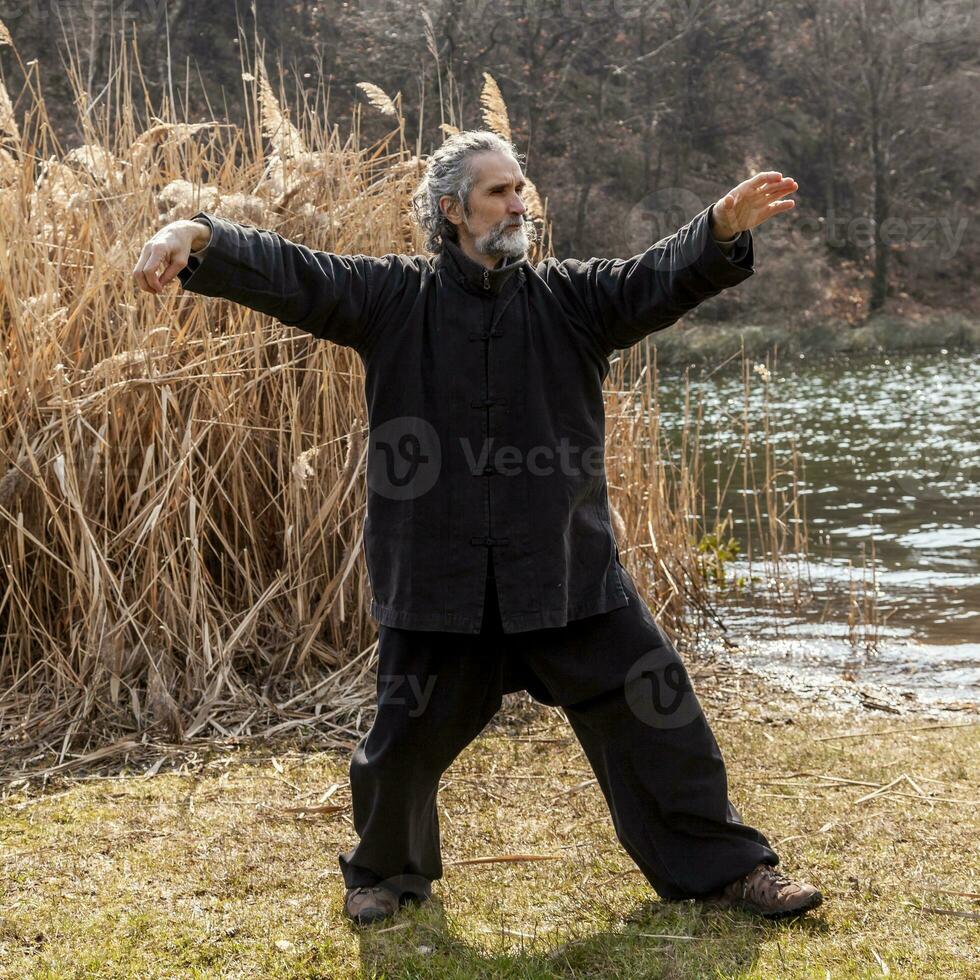 maduro homem praticando tai chi disciplina ao ar livre foto