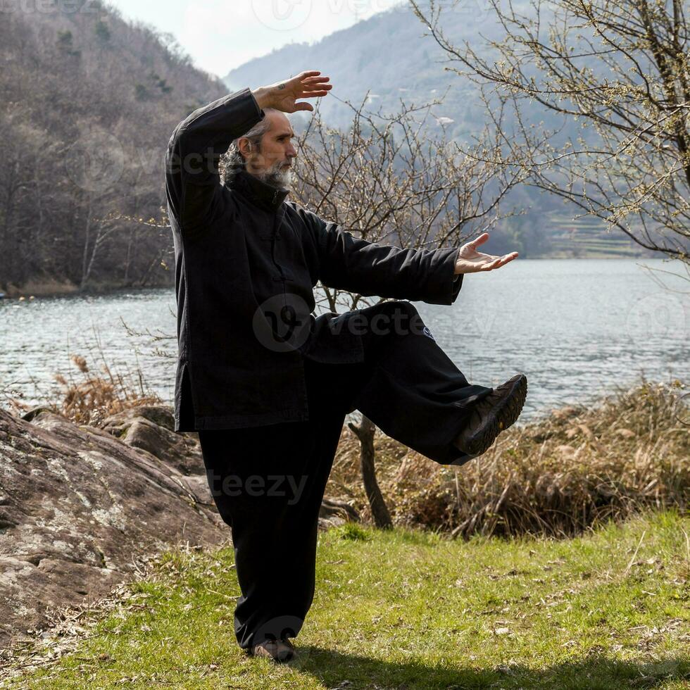 maduro homem praticando tai chi disciplina ao ar livre foto