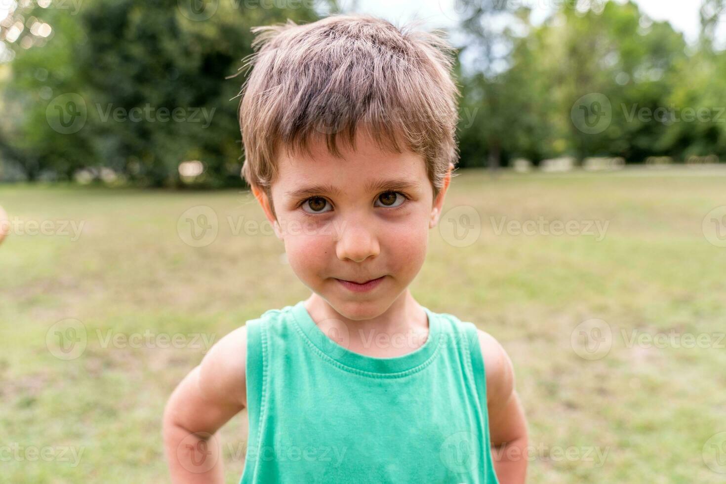 retrato do fofa sorridente Garoto dentro uma público parque foto