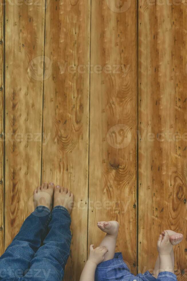dois jovem irmãos deitado em seus cama. crianças tendo Diversão. dois pequeno irmãos levantando seus pernas contra a de madeira escrivaninha. foto