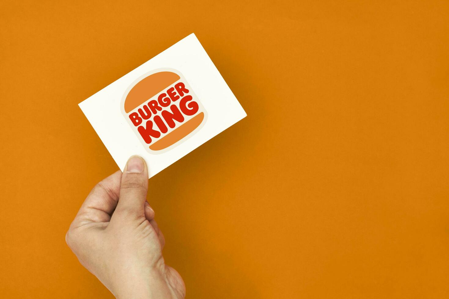 mão detém uma cartão com hamburguer rei logotipo foto