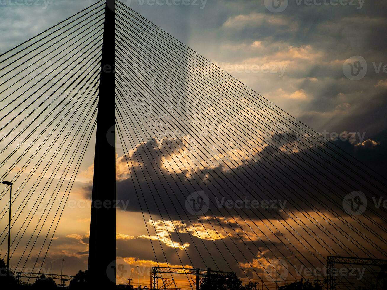 grande suspensão ponte torre às pôr do sol - raios solares estourando através a nuvens foto