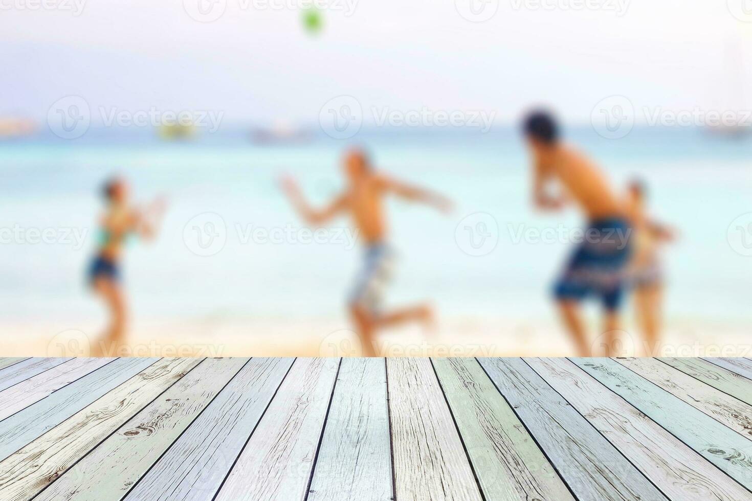 branco madeira mesa em borrado jovem turistas jogando bola em de praia foto