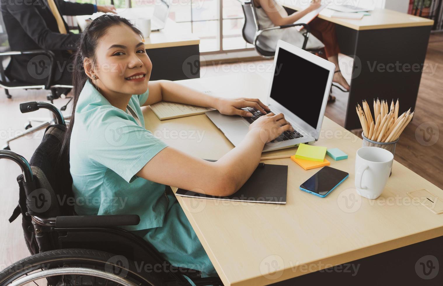 mulher com deficiência sentada em cadeira de rodas a trabalhar no escritório foto