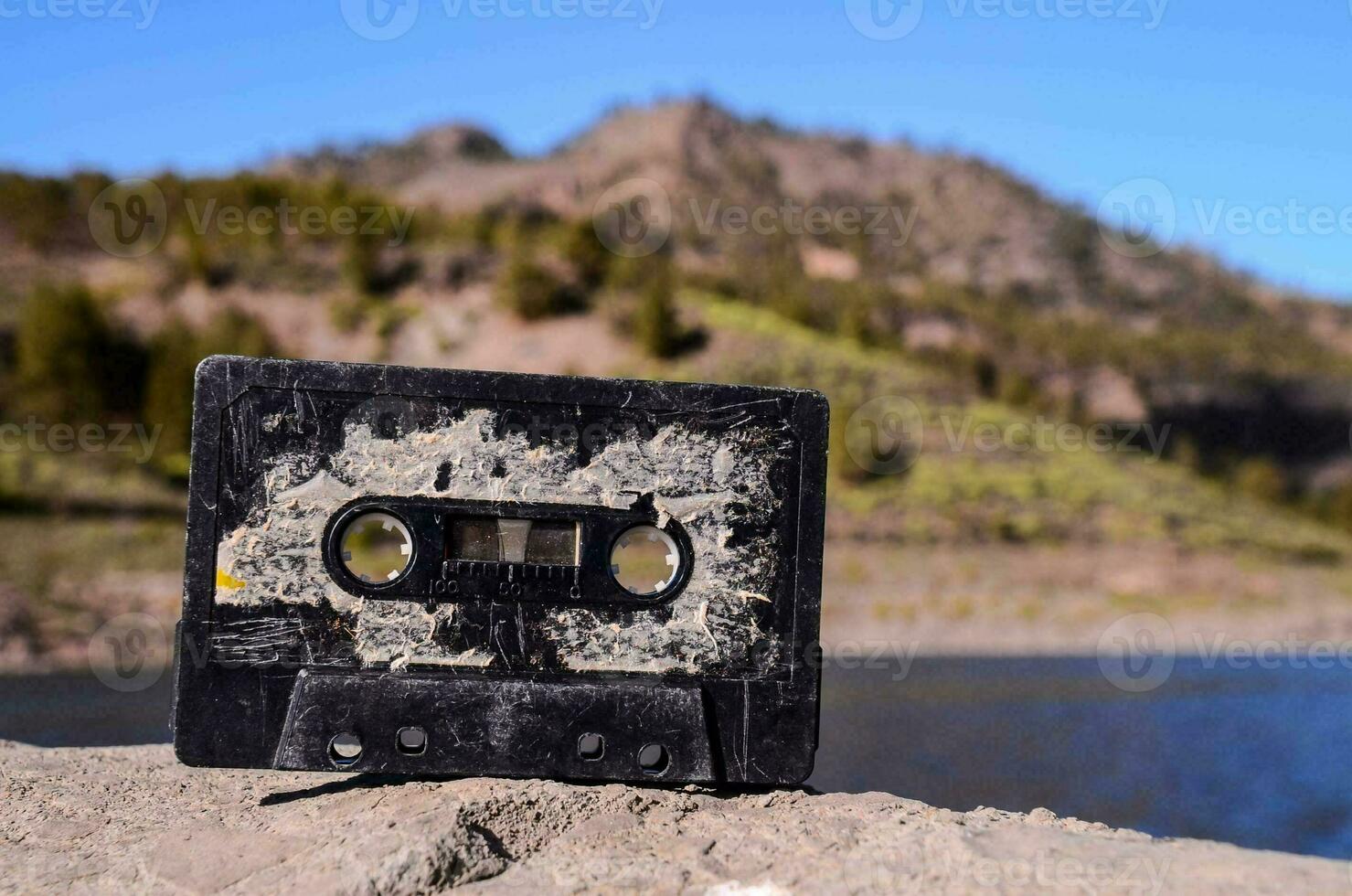 uma cassete fita senta em a terra perto uma lago foto