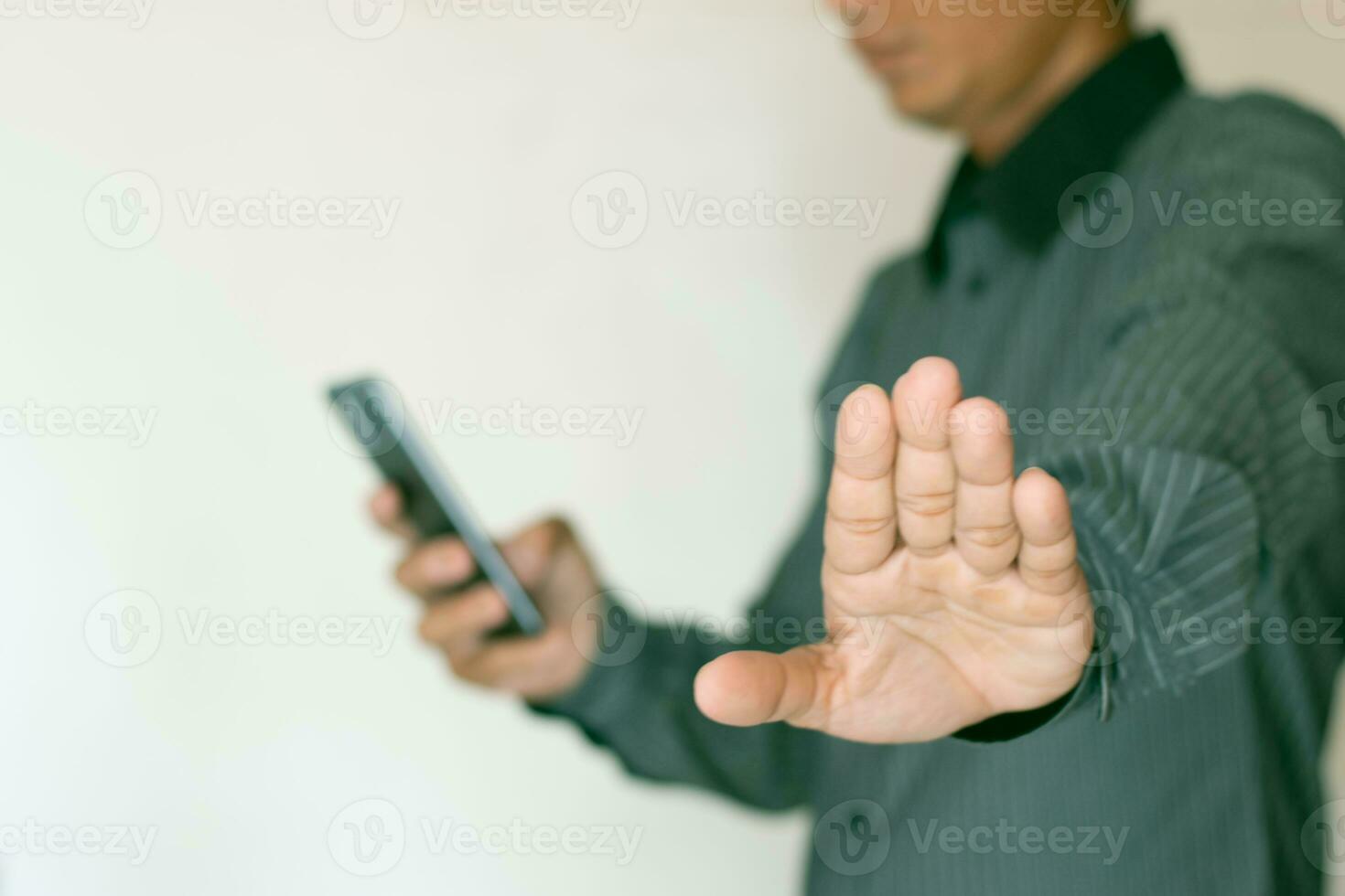 fechar acima cenas mostra uma homem usando uma Smartphone e estendendo dele mão contra uma branco fundo. foto