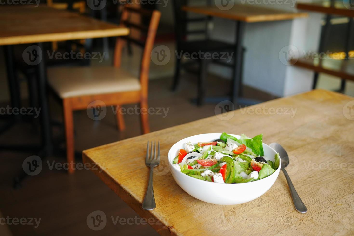 salada grega em uma tigela sobre uma mesa de café. foto