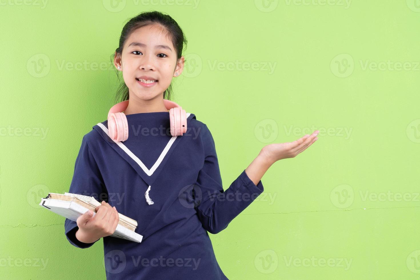 retrato de criança asiática segurando um livro sobre fundo verde foto