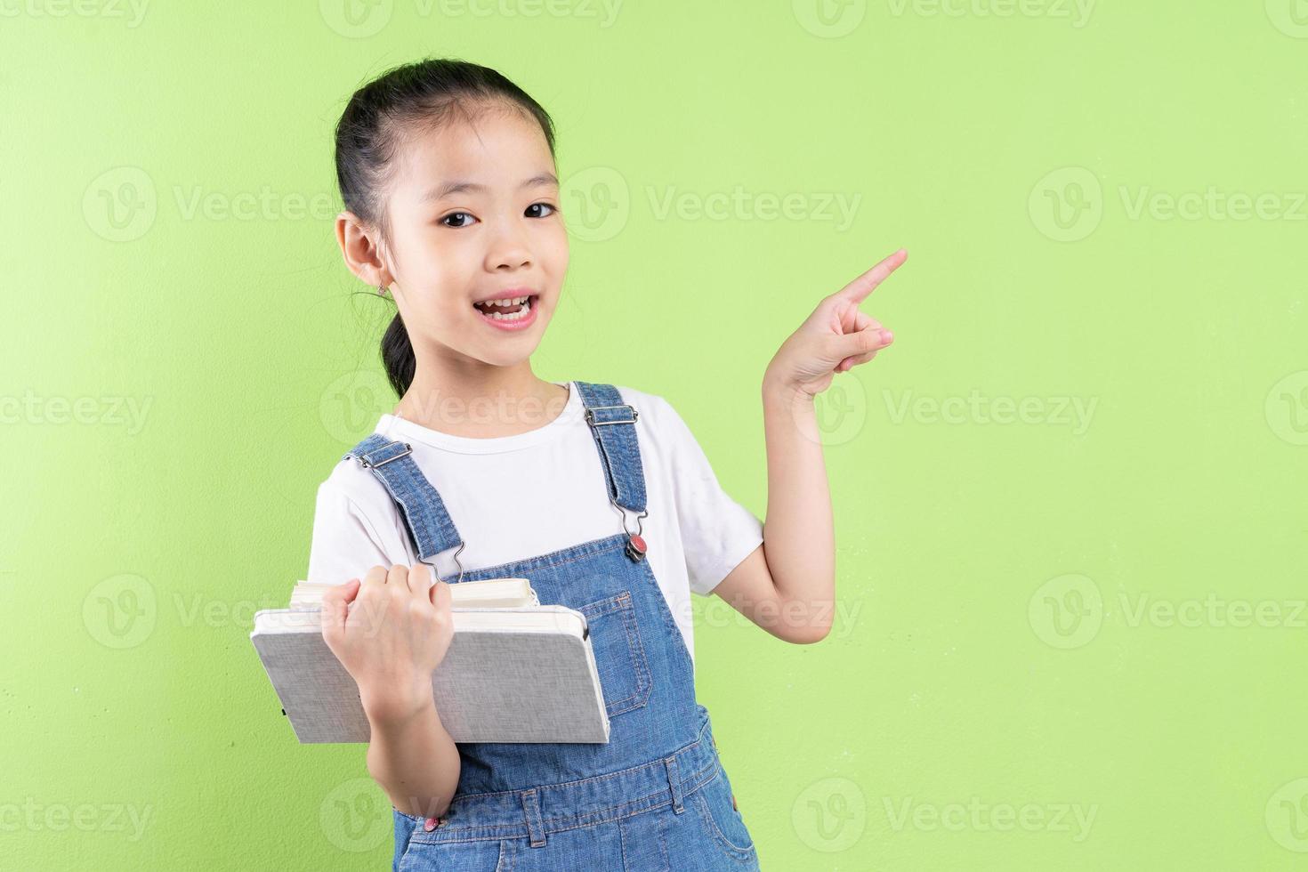 retrato de criança asiática segurando um livro sobre fundo verde foto