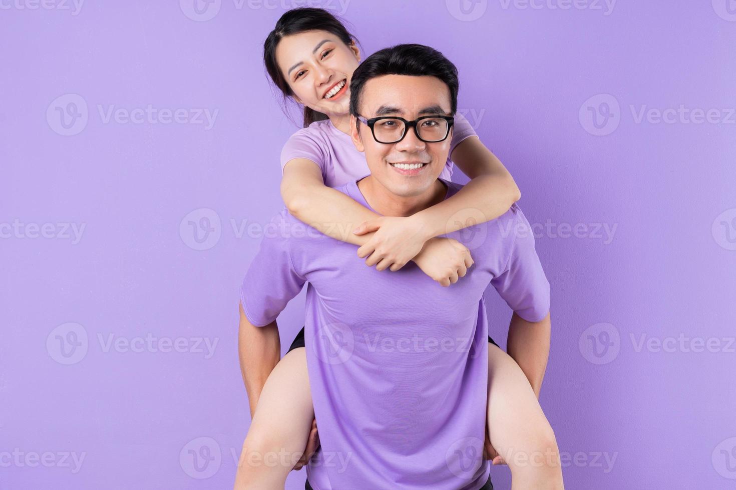jovem casal asiático posando em fundo roxo foto