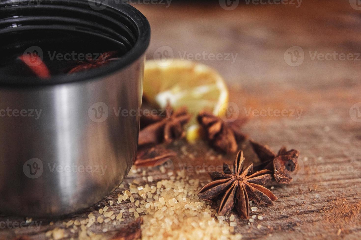 vinho quente em um copo com canela, limão em uma tábua de madeira foto