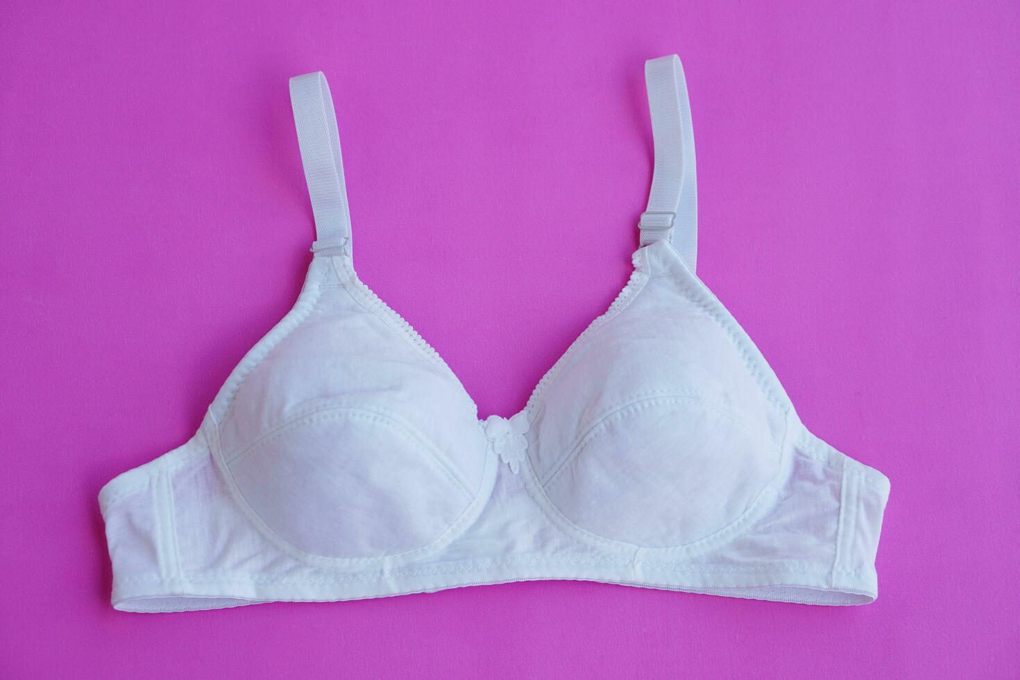 branco algodão sutiã em Rosa fundo. conceito, feminino sutiã. clássico confortável com copo uma para fêmea jovem adolescentes. proteger e aguarde lindo seios. seio Câncer consciência foto