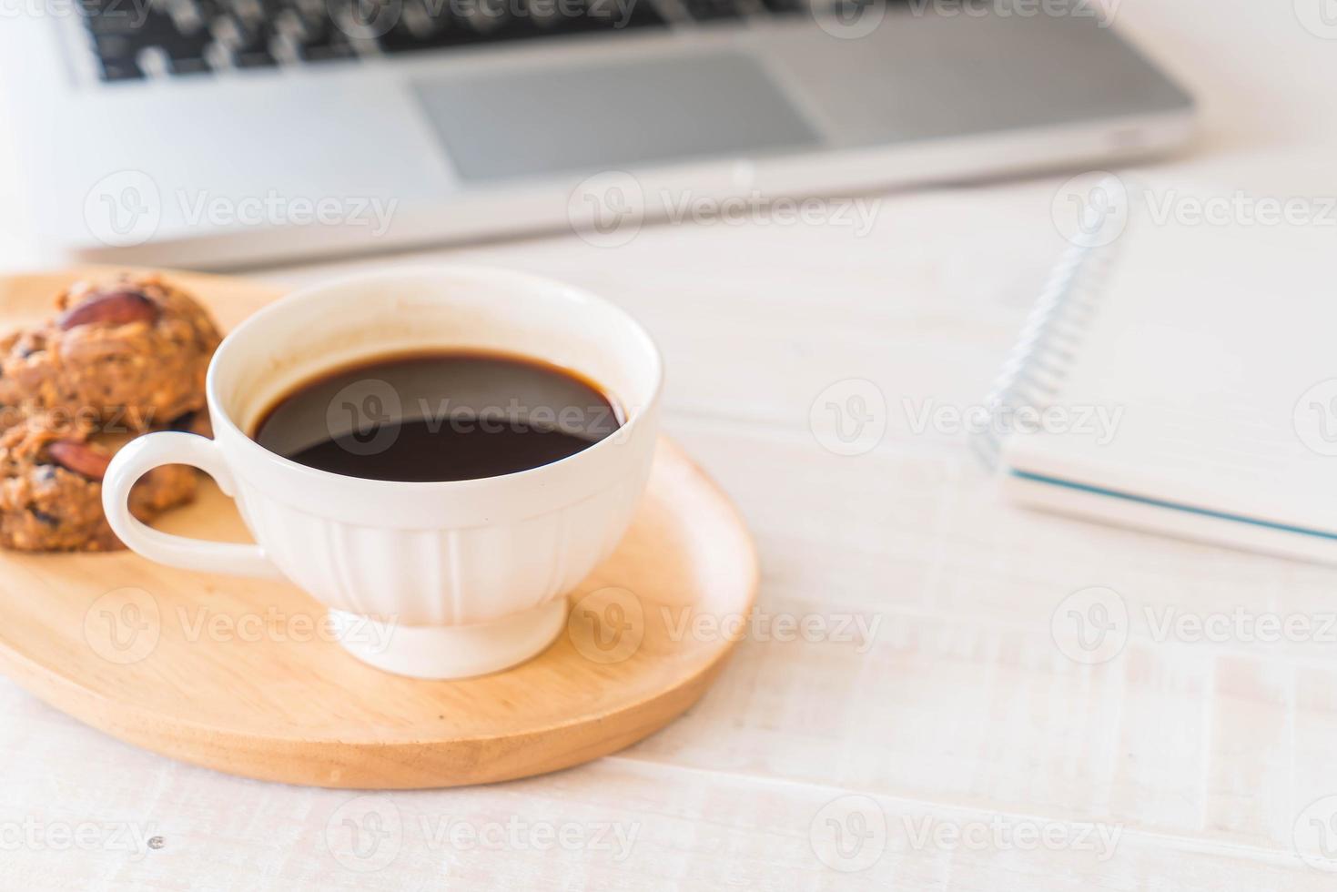 café preto e biscoitos com laptop e notebook na mesa foto