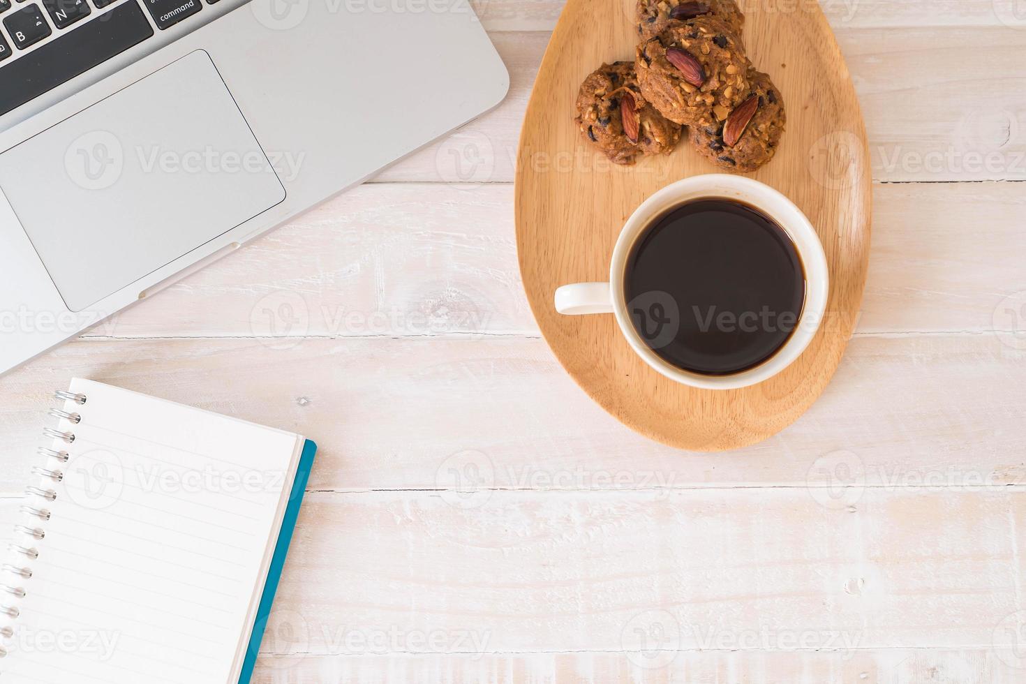 café preto e biscoitos com laptop e notebook na mesa foto